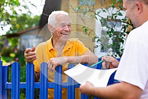 Grandfather talking to census agent standing at fence of his country house