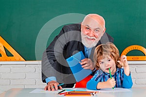 Grandfather teacher with grandson pupil at back of classroom at the elementary school. Science education concept.