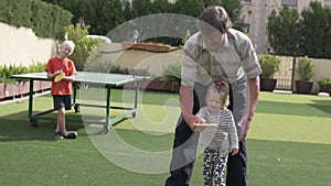 Grandfather teaches grandchildren to play table tennis