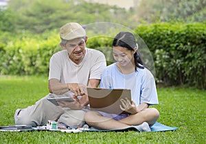 grandfather teaches granddaughter to draw picture by using digital internet online on tablet technology