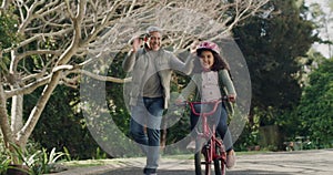 Grandfather teaching child to cycle on her first bike ride, happy child outdoors learning on a bicycle in a street