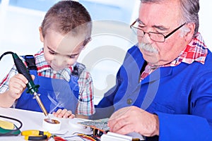 Grandfather teaching grandchild to use soldering resin