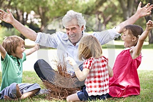 Grandfather Teaching Grandchildren To Build Camp Fire