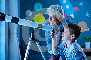 Grandson with grandfather stargazing at night with a telescope