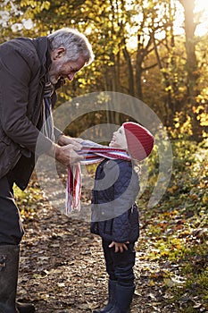 Grandfather Tying Granddaughter`s Scarf On Autumn Walk