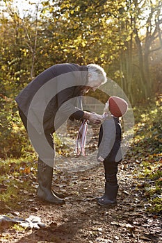 Grandfather Tying Granddaughter`s Scarf On Autumn Walk