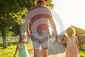 Grandfather walking with his granddaughters on the farm.