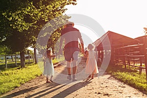 Grandfather walking with his granddaughters on the farm.