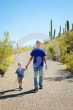 Grandfather and Young Grandson Hike Downhill, Holding Hands on a