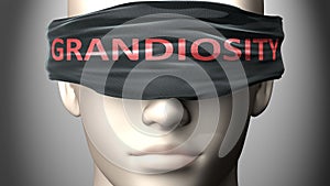 Grandiosity can make things harder to see or makes us blind to the reality - pictured as word Grandiosity on a blindfold to photo