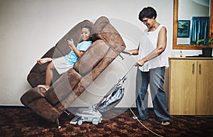 Grandma, boy and vacuum in home portrait, play games and lazy to clean for housework. Grandparent, grandson and bonding