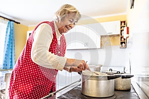 Grandma cooks bryndzove halusky, a traditional Slovak dish, on her old oven. A pensioner cooks food in her kitchen