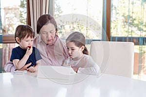 Grandma entertaining her little grandchildren with a tablet computer game