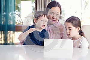 Grandma entertaining her little grandchildren with a tablet computer game