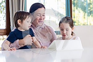 Grandma entertaining her little grandchildren with a tablet computer game