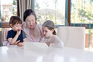 Grandma entertaining her little grandchildren with a tablet computer game