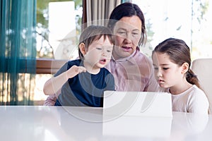 Grandma entertaining her little grandchildren with a tablet computer game