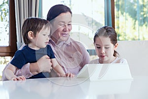 Grandma entertaining her little grandchildren with a tablet computer game