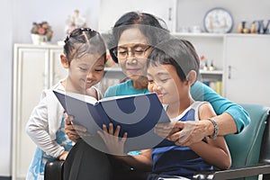 Grandma and grandchildren reading book together