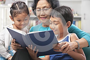 Grandma and grandchildren reading book together