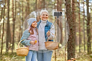Grandma with granddaughter taking selfie in forest