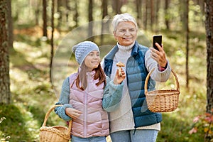 Grandma with granddaughter taking selfie in forest