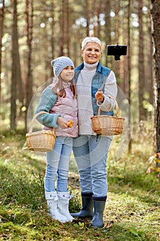 Grandma with granddaughter taking selfie in forest