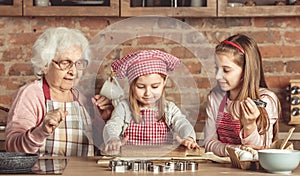 Grandma and granddaughters spreading dough