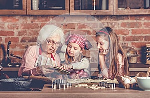 Grandma and granddaughters spreading dough