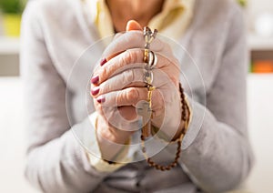 Grandma holding wooden rosary and praying