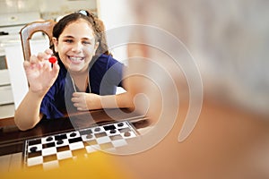 Grandma Playing Checkers Board Game With Granddaughter At Home