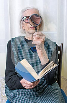 Grandma reading a book through magnifying glass