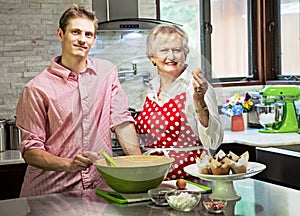 Grandmother baking cupcakes with her grandson