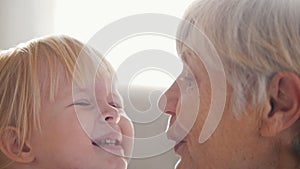 Grandmother being tenderness with her granddaughter, kissing her in chin
