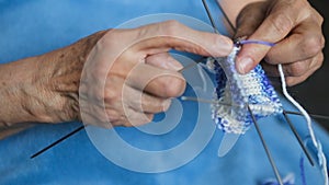 Grandmother in a blue robe knits