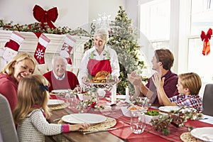 Grandmother Bringing Out Turkey At Family Christmas Meal photo