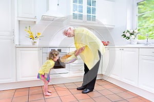Grandmother and charming girl baking pie in white kitche photo