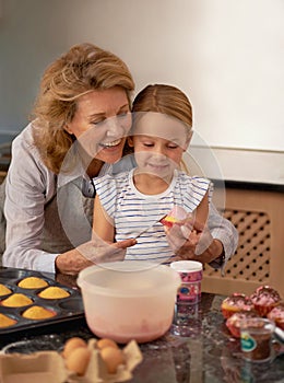 Grandmother, child and baking cupcake in kitchen or helping with decoration or creative icing, sprinkles or teamwork