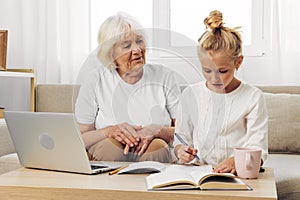 Grandmother child family bonding education selfie smiling video granddaughter laptop sofa togetherness call hugging