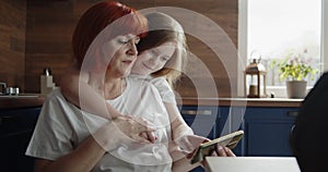 Grandmother and child using a smartphone together at home