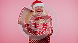 Grandmother in Christmas sweater smiling, unwrapping gift, opening box with pet cat, great surprise photo