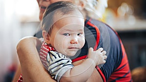 Grandmother cradling crying infant baby girl looking at camera