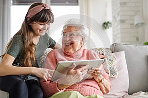 Grandmother with cute girl scrolling on tablet, girl teaching senior woman to work with technology, internet. Portrait