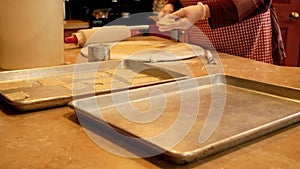 Grandmother cuts and transfers tasty homemade cookie dough onto baking sheets.