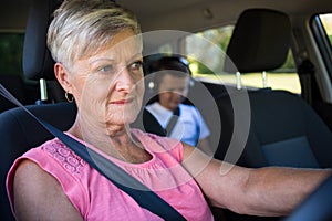 Grandmother driving a car while grandson sitting in the back seat