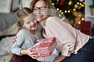 Grandmother embracing and giving her granddaughter a Christmas gift