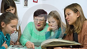 Grandmother and four granddaughters watching old photo album at home