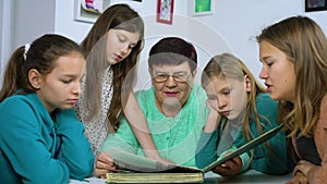 Grandmother and four granddaughters watching old photo album at home