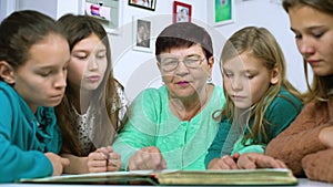 Grandmother and four granddaughters watching old photo album at home