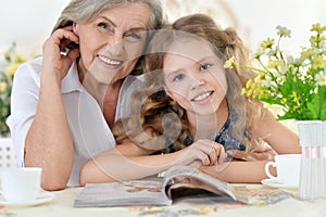 Grandmother with girl reading magazine